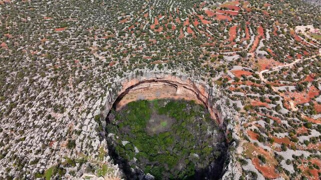 Lush greenery framing deep karst sinkholes cennet and cehennem, revealing dramatic geological erosion patterns in rugged mersin landscape, turkey