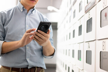 Asian man is using his mobile phone in front of the express delivery locker