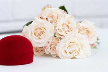 a beautiful bouquet of creamy-white roses in full bloom, A red velvet box in the foreground. Wedding, anniversary, or Valentine's Day
