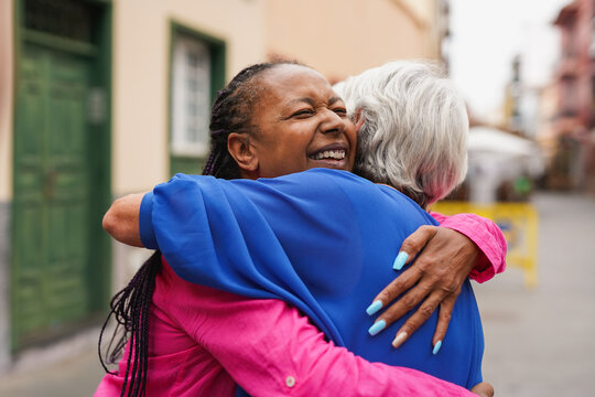 Multiracial senior women meeting each other in the city while hugging together - Elderly people, lifestyle and friendship concept