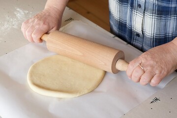 woman rolls out dough with a rolling pin