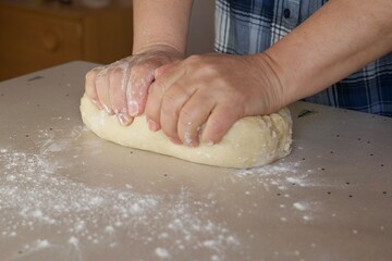 a woman kneads dough on the table with her hands