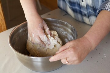 Fototapeta premium girl kneading dough with her hands in a metal bowl