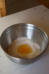 Flour and cracked eggs in a metal bowl