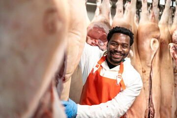 Food factory worker or butcher moving fresh raw meat in slaughterhouse.