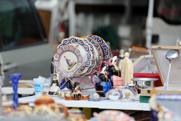 Lively flea market scene in France with vintage items, antiques, books, and decorations. People...