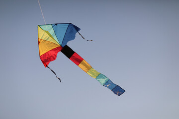 Evening at the beach with a boy flying a kite. Silhouette against sunset over the sea, evoking freedom, play, and peaceful coastal atmosphere.