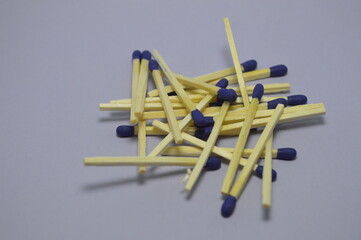 A close up of a set of wooden matches arranged on an isolated dark background. The match heads are blue in color and the wooden sticks have a natural texture. The sticks are ready to use.