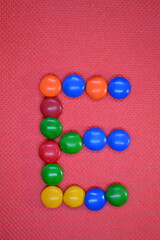 colored chocolate coated candy alphabet on pink background E