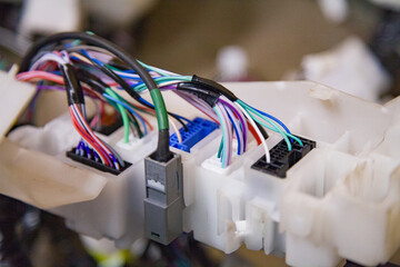 Multicolored thin wires connected to connectors, modules, and connections from a new car wiring harness to replace the old wiring in a vehicle
