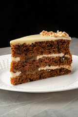 Delicious slice of layered cake with creamy frosting and nuts served on an elegant plate