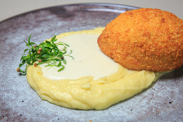  a classic and comforting dish, likely a variation of a schnitzel or chicken-fried steak, served with mashed potatoes and a creamy sauce.