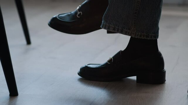 Unrecognizable woman wearing jeans and loafers uncrossing her legs while sitting at business meeting