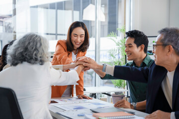 Corporate professionals linking hands, symbolizing unified teamwork and collaborative success during strategic business meeting