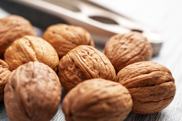 Whole walnuts with a nutcracker. Close-up of textured brown shells. Healthy snack rich in nutrients and omega-3. Selective focus. 
