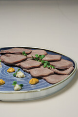 The image depicts a beautifully presented dish featuring slices of beef tongue.