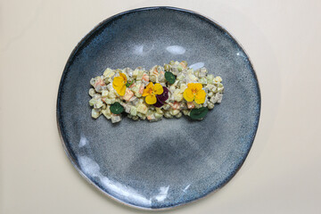 beautifully presented Russian salad, also known as Olivier salad, served on a blue-gray ceramic plate. 