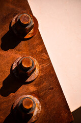 Dettaglio di tre bulloni arrugginiti su una lastra ossidata