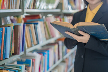 Asian students sit at tables in the library reading, studying, writing, and researching information.