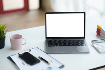 Contemporary workspace displaying laptop with blank screen, smartphone, documents, calculator,...