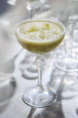 The image shows a beautifully presented matcha green tea latte or cocktail. 