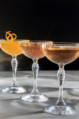 The image shows three elegant cocktail glasses with different colored drinks. 