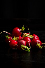 Top view of radishes on table and black background, vertical with copy space