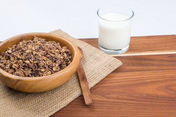 Muesli in a bowl and a glass of milk on a wooden table