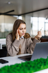 Bored young woman in the office working with a laptop