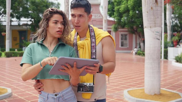 Young tourists exploring city with tablet, getting lost and having fun