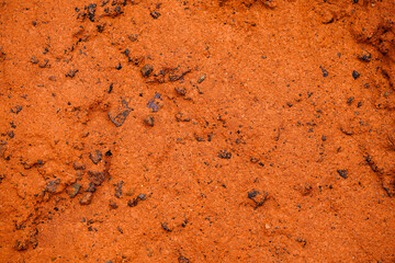 The surface of red clay with small stones and irregularities