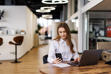 Busy business woman using laptop working in corporate office.