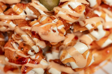 Chicken with fires topped with sauce, close up, macro view