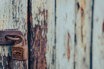 Old rusty padlock with shabby green painted wooden surface background texture
