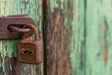 Old rusty padlock with shabby green painted wooden surface background texture