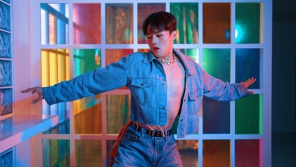 Close up of asian performer with sun glasses moving freestyle dance while looking at camera at nightclub. Happy street dancer dancing and show footstep with colorful bright neon light. Regalement.