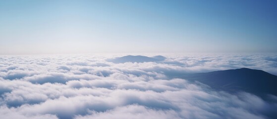 Fototapeta premium Elevated view above clouds at sunrise, revealing peaks poking through a sea of soft white beneath a gentle pastel sky.