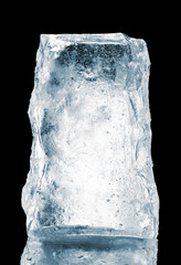 Crystal clear illuminated natural ice block on a black background with reflective surface.