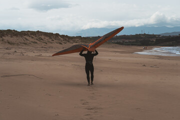 A man performs kite surfing on the sunny Liencres beach, with the Cantabrian Sea in the background....