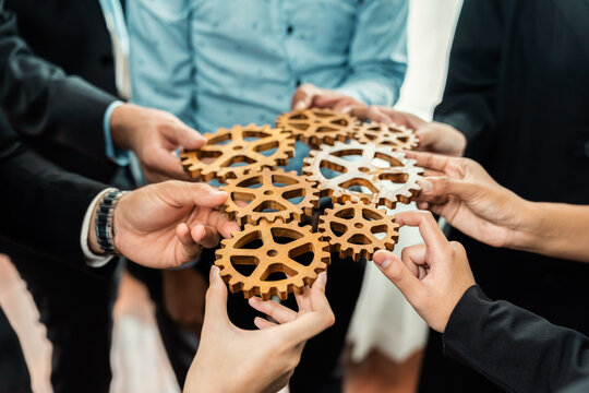 Group of multiracial business people joining gear wheels together as effective unity and productive teamwork concept. Efficient system business team process for solution solving. Meticulous
