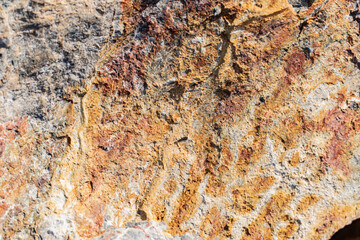 The background is a beautiful rough stone texture in close-up with bright colors of mineral inclusions