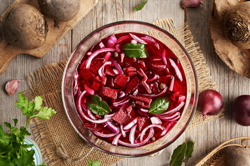 Preparation of fermented beet kvass in a glass bowl with fresh beetroot, onions, garlic and spices