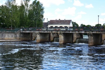 An old dam in Sventoji river. Pedestrian bridge and river dam in the summer day.