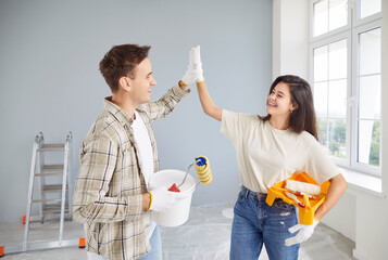 Happy family couple gives each other a high five during new home renovation and painting. Teamwork...