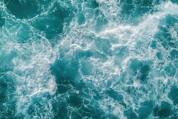 Fototapeta premium Aerial view of ocean water in turquoise tones, with splashes and foam providing a stunning natural texture