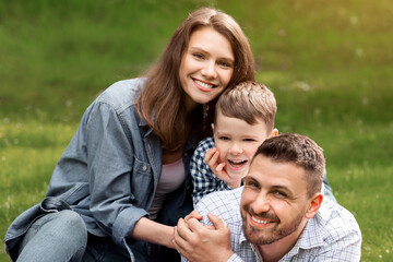 Fototapeta premium Summertime family activities. Joyful parents with son enjoying their picnic outdoors, copy space. Panorama