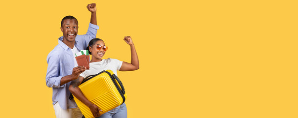 Young African American woman holds suitcase, man holds passport with tickets, both gesturing yes,...