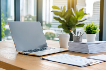 Fototapeta premium Modern workspace with laptop, stationery, and greenery during daylight