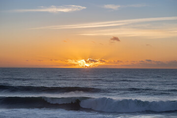 Fototapeta premium sunset over the Atlantic Ocean in Ericeira, Portugal. Golden light reflects on the waves, creating a peaceful and dramatic coastal scene. Perfect for travel, nature, and landscape photography.