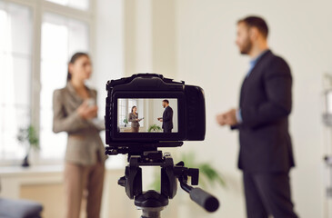 Close up view of a video camera recording an interview or hosting a live broadcast. The scene...